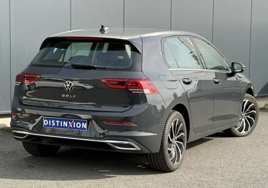 Volkswagen Golf VIII gris Urano vue 3/4 arrière droit, avec jantes alliage et feux arrière LED distinctifs.