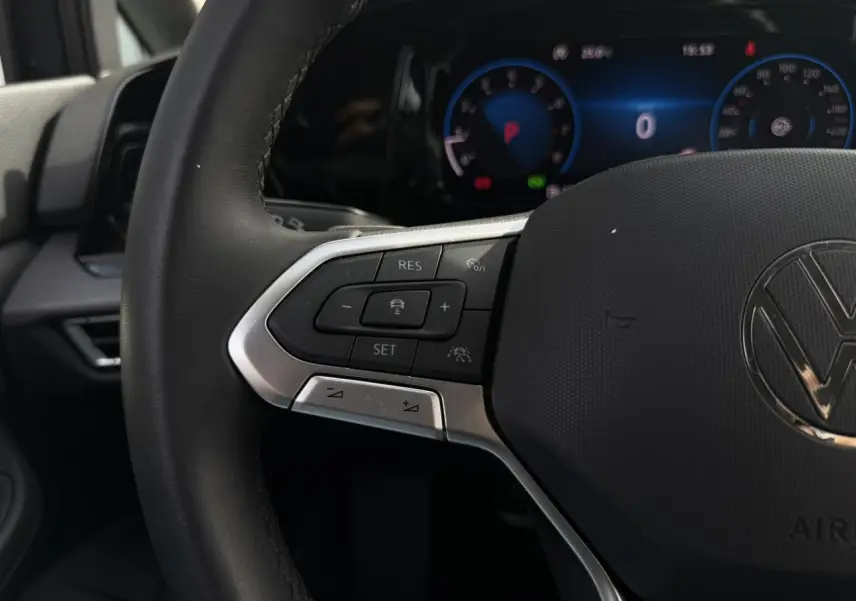Gros plan sur le volant multifonctions cuir de la Volkswagen Golf VIII 2024 avec commandes intégrées et tableau de bord numérique.