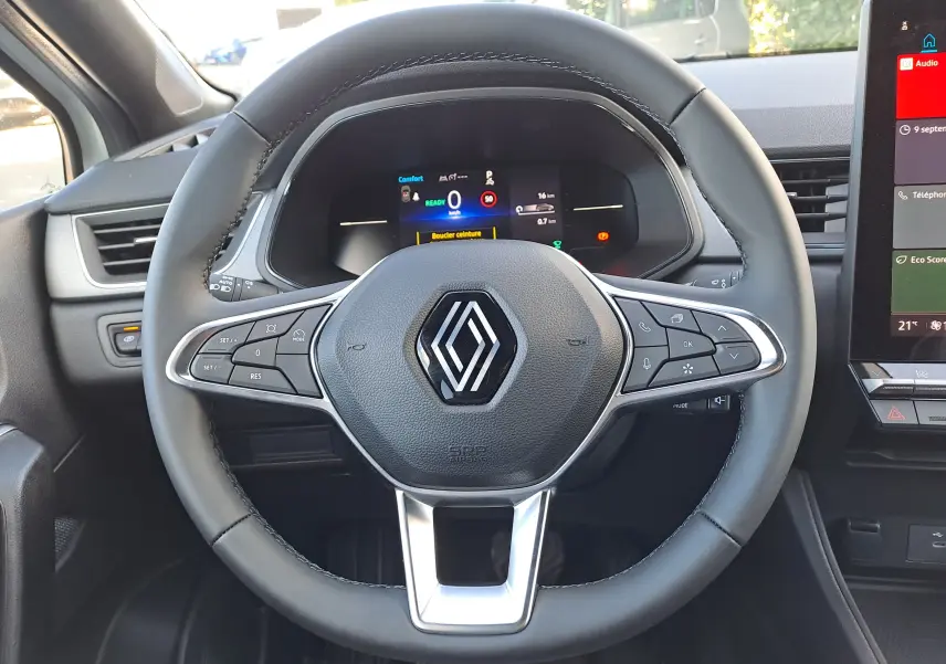 Vue rapprochée du volant noir du Renault Captur 2025 avec commandes intégrées et tableau de bord numérique allumé.