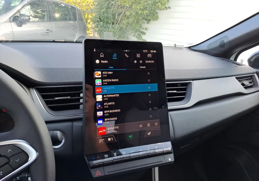 Vue intérieure du tableau de bord du Renault Captur 2025 avec écran tactile central affichant les stations radio, ambiance sobre en gris.