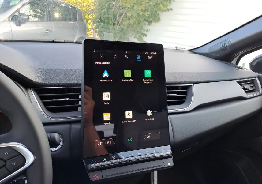 Vue intérieure du tableau de bord du Renault Captur 2025, avec grand écran tactile central et commandes climatisation.