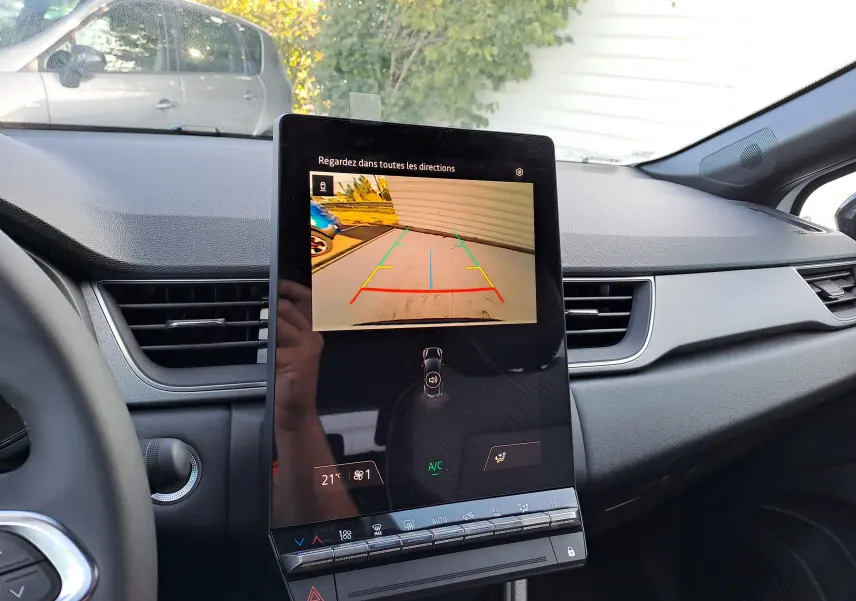 Vue intérieure du tableau de bord du Renault Captur 2025, écran central affichant la caméra de recul et commandes climatisation.