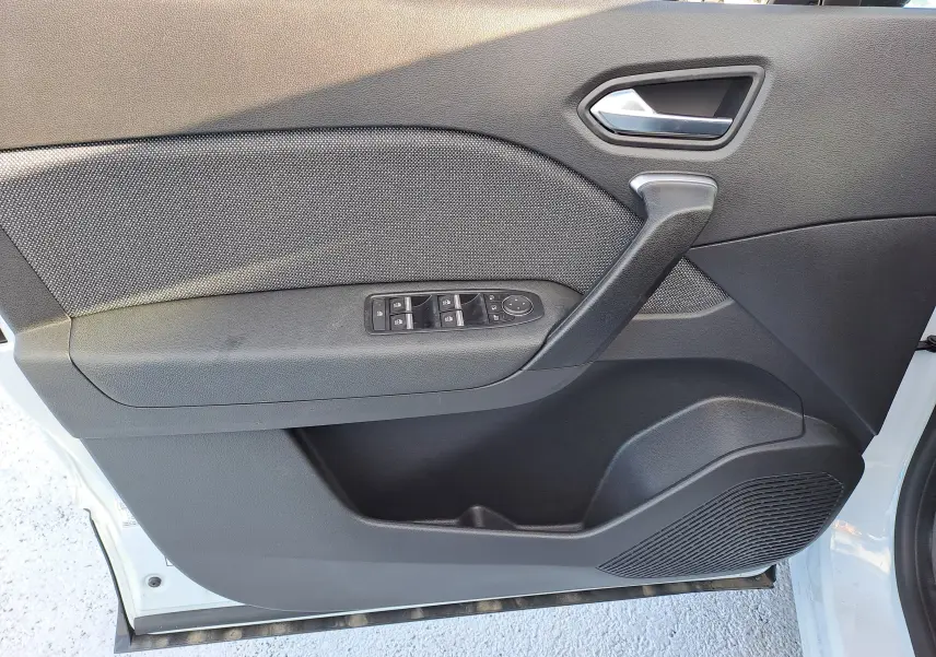 Vue intérieure côté gauche de la porte avant d'un Renault Captur blanc nacré avec commandes électriques des vitres.