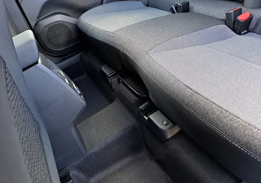 Vue rapprochée de la banquette arrière grise en tissu du Renault Captur 2025, mettant en valeur les ceintures de sécurité et le sol noir.