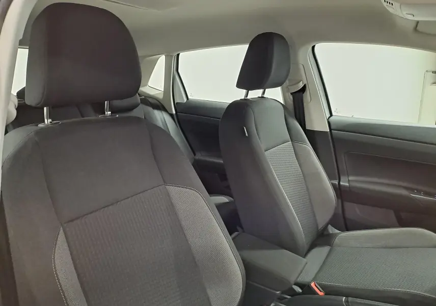 Vue intérieure des sièges avant noirs de la Volkswagen Polo 2024, version Life Plus, avec détails tissu et ceintures visibles.