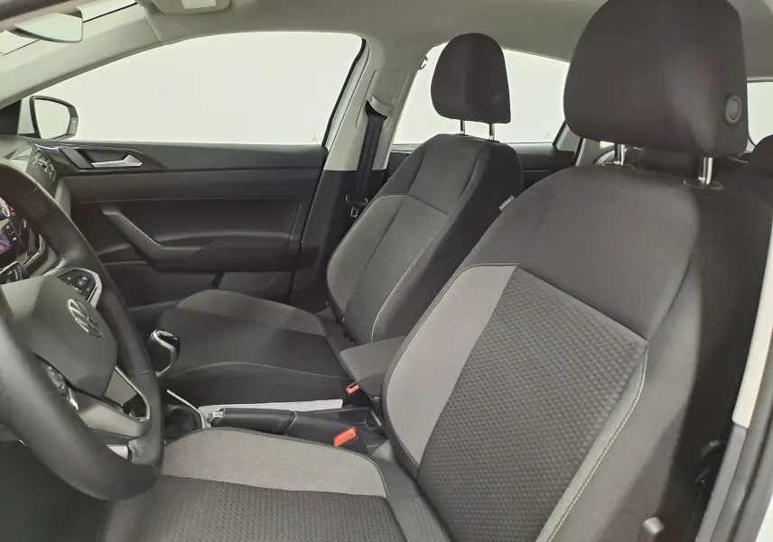 Vue intérieure côté conducteur de la Volkswagen Polo 2024 blanche, montrant les sièges avant en tissu bicolore et la console centrale.