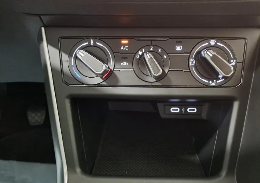 Gros plan sur les commandes de climatisation manuelle et les ports USB de la Volkswagen Polo blanc pur 2024.
