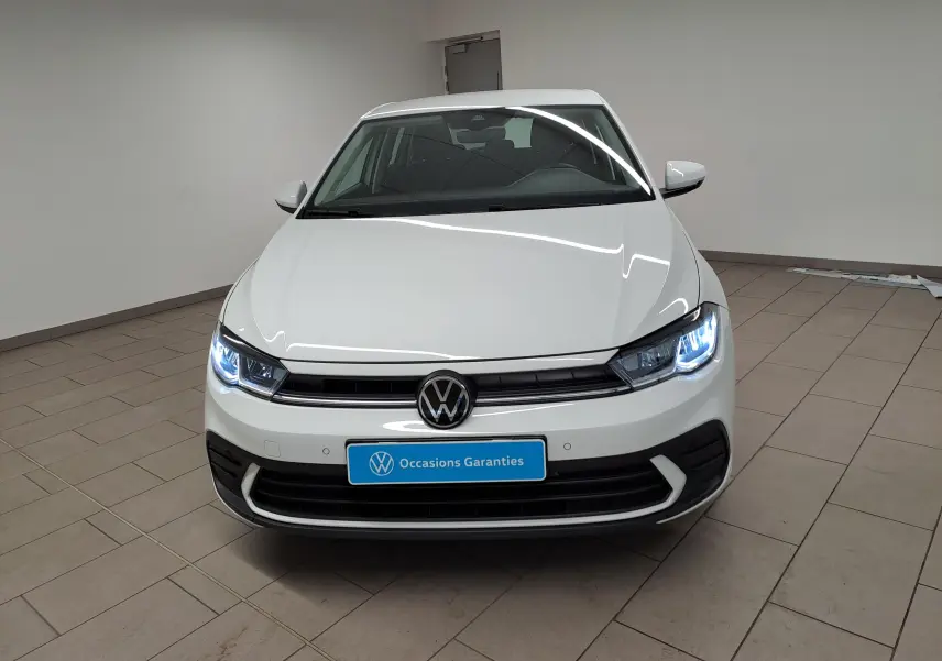 Vue avant d'une Volkswagen Polo blanc pur 2024 avec phares allumés dans un showroom intérieur.