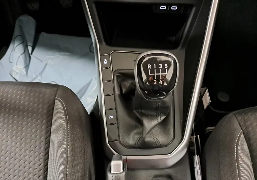 Vue plongeante sur la console centrale d'une Volkswagen Polo 2024, boîte manuelle avec levier de vitesses en cuir noir.