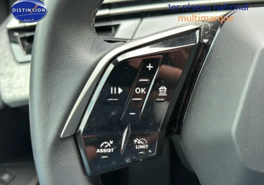 Gros plan sur les commandes multifonctions noires du volant cuir du Peugeot 3008 gris titane, version 2025 hybride.