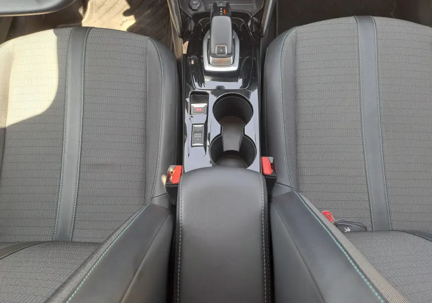 Vue plongeante sur la console centrale noire et les sièges tissu gris du Peugeot 2008 1.5 BlueHDi 130 Diesel de 2021.