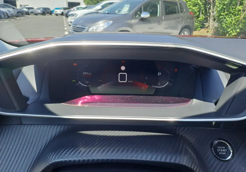 Tableau de bord numérique du Peugeot 2008 rouge 2021, affichant la vitesse à 0 km/h et le bouton start/stop.