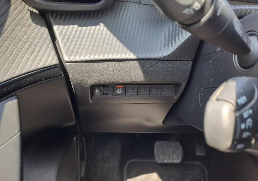 Vue rapprochée du tableau de bord côté gauche du Peugeot 2008 rouge 2021, avec commandes d'éclairage et bouton de désactivation d'assistance.