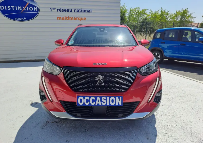 Vue frontale d'un Peugeot 2008 rouge 2021 avec calandre noire et plaque "OCCASION" visible au centre.