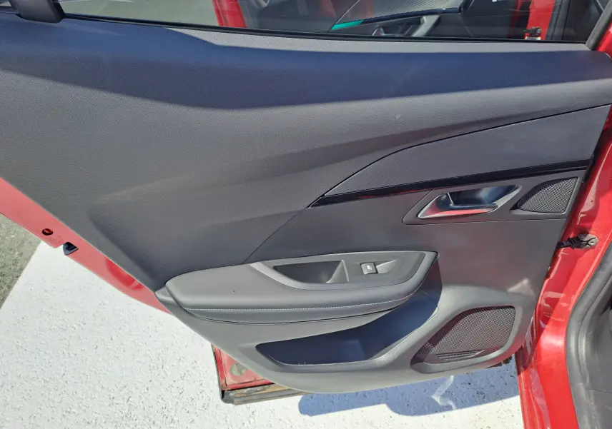 Vue rapprochée de la porte arrière droite rouge du Peugeot 2008 2021 avec garniture noire et commande de fenêtre.