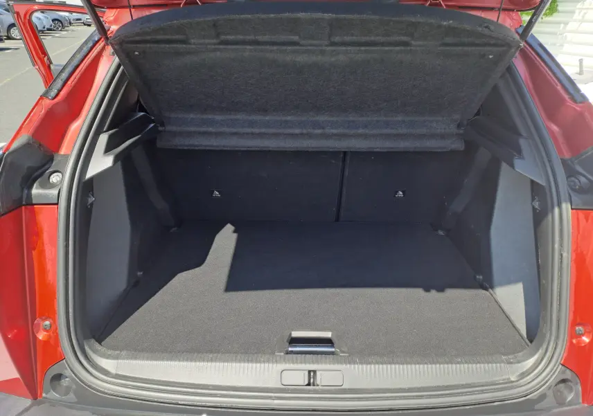 Coffre ouvert d'un Peugeot 2008 rouge 2021, vue arrière montrant l'espace de chargement vide et la trappe de plancher.