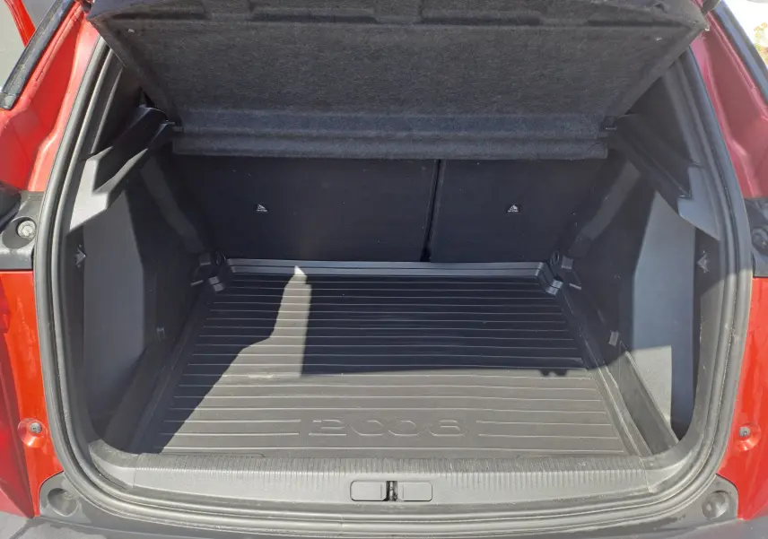 Coffre ouvert vu de l'arrière d'un Peugeot 2008 rouge, avec tapis de coffre noir marqué 2008.