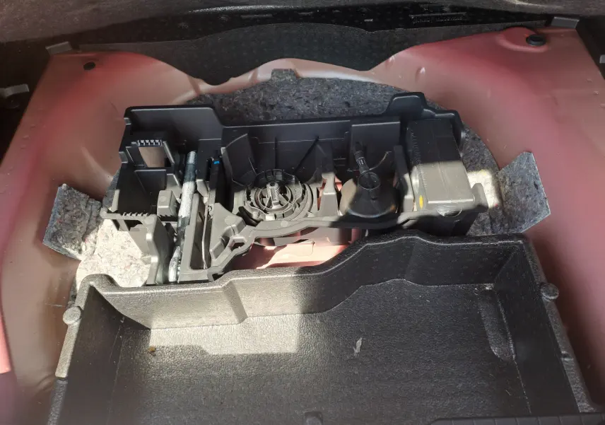Compartiment de rangement sous le coffre d'une Peugeot 2008 rouge, montrant les outils et l'aménagement intérieur.