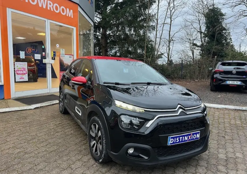 Citroën C3 Shine 2023 noir avec toit rouge, vue 3/4 avant droit devant un showroom orange.