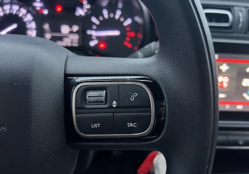 Gros plan sur les commandes audio au volant à droite du tableau de bord d'une Citroën C3 Shine 2023 noir toit rouge.