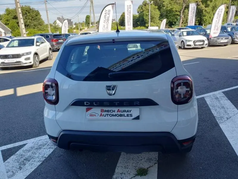 Vue arrière d'un Dacia Duster blanc Glacier 2021 stationné devant un concessionnaire Brech Auray Automobiles.
