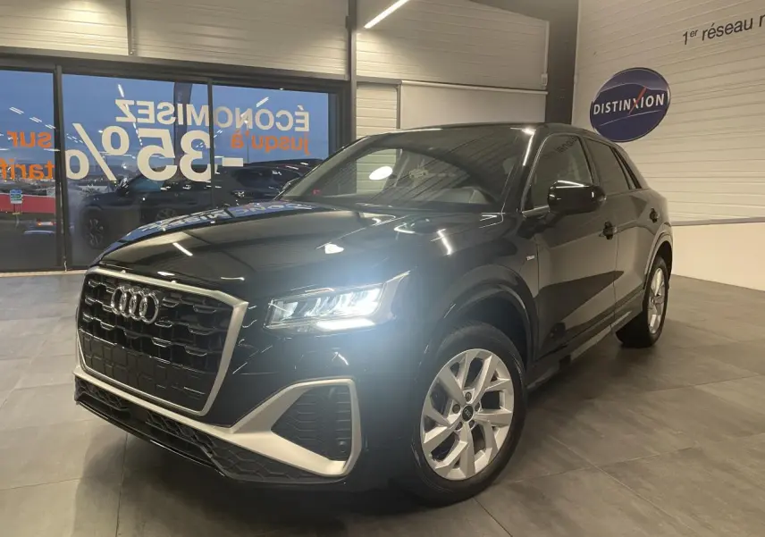 Audi Q2 noir métallisé en 3/4 avant droit avec phares allumés et jantes alliage 18 pouces style trapèze.