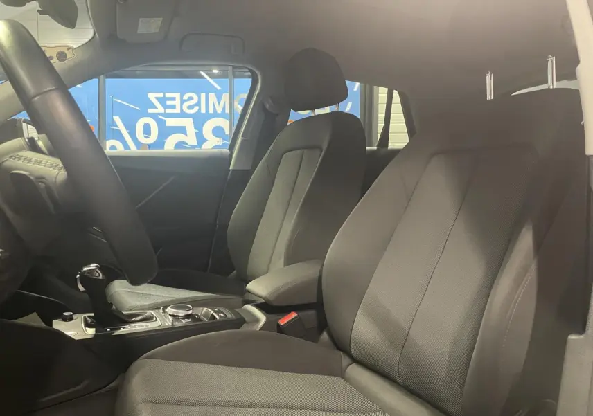 Vue intérieure côté droit montrant les sièges avant en tissu noir et la console centrale d’un Audi Q2 noir métallisé.