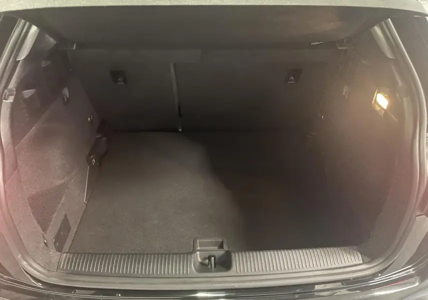 Coffre ouvert vu de face d’un Audi Q2 noir métallisé 2023, espace de chargement vide avec éclairage intérieur.