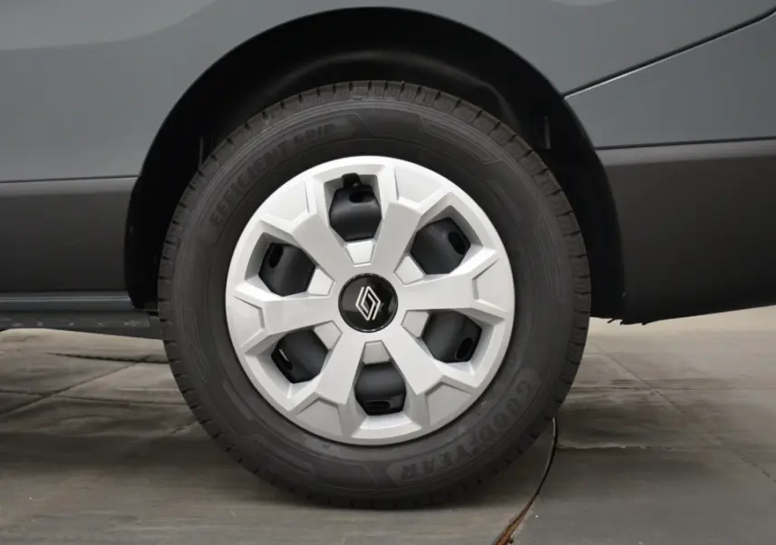 Gros plan sur la roue arrière droite d’un Renault Trafic Fourgon gris clair, avec jante en plastique et pneu Goodyear.