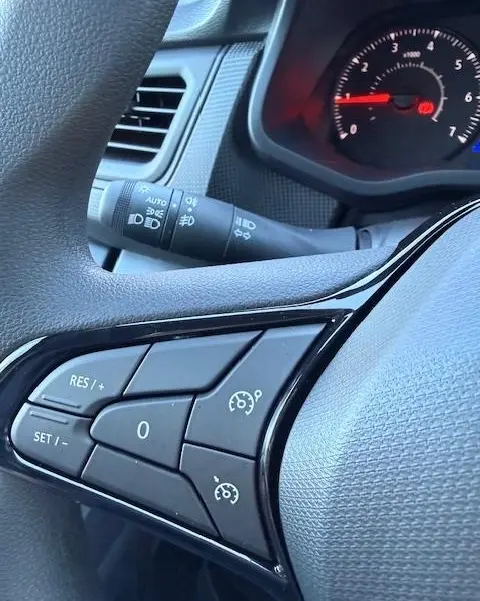 Gros plan sur les commandes du volant multifonctions du Renault Trafic Fourgon gris clair, avec régulateur de vitesse visible.