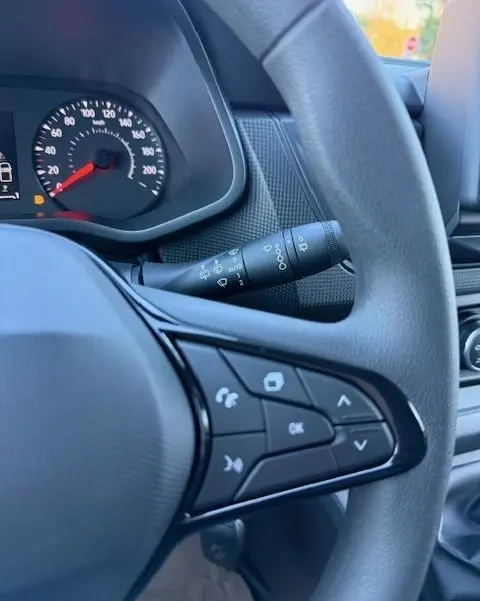 Gros plan sur le volant multifonctions gris du Renault Trafic Fourgon 2025 avec tableau de bord et commandes visibles.