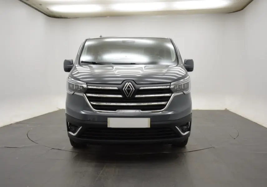 Vue frontale d'un Renault Trafic Fourgon gris clair 2025 avec calandre chromée et phares LED.