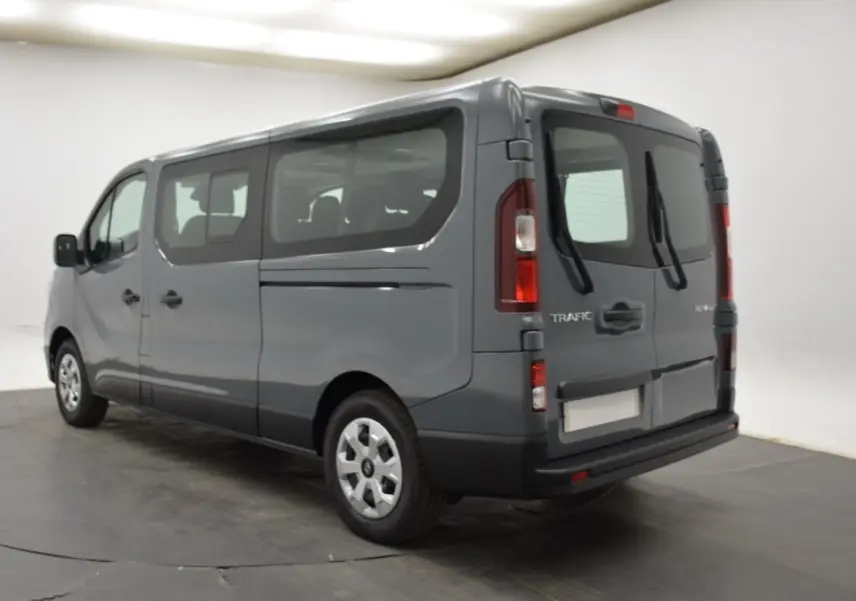 Renault Trafic Fourgon gris clair vu en 3/4 arrière droit, avec vitres latérales et portes arrière battantes.