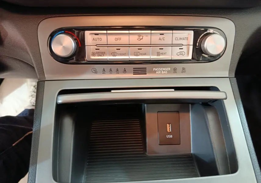 Vue rapprochée de la console centrale du Hyundai Kona électrique 2022, avec commandes climatisation et prise USB visible.