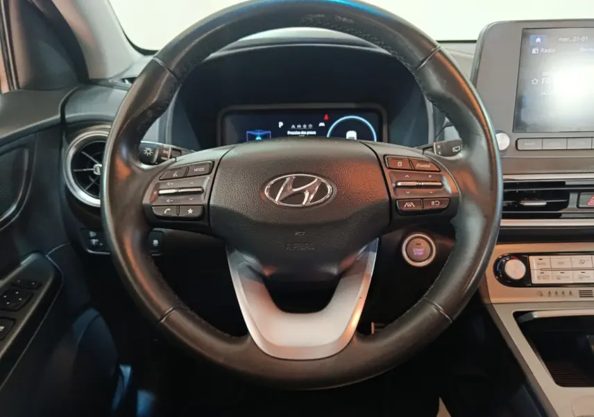 Vue intérieure centrée sur le volant noir de la Hyundai Kona électrique 2022 avec tableau de bord et écran tactile.