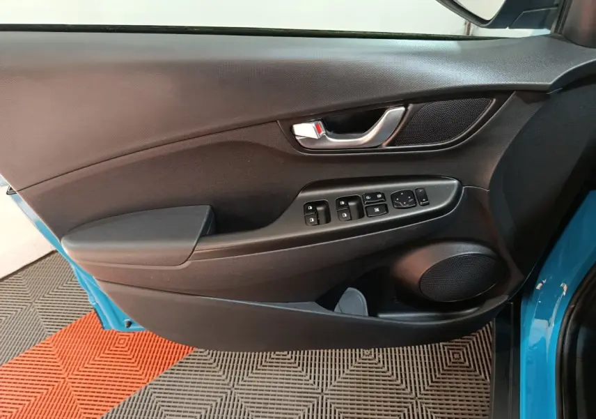 Vue rapprochée de la porte avant gauche noire avec commandes électriques sur Hyundai Kona bleu électrique 2022.