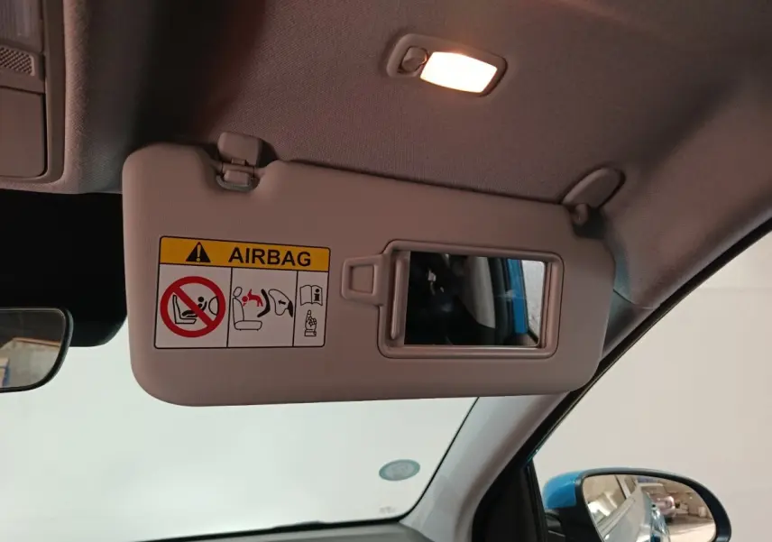 Détail du pare-soleil côté conducteur avec miroir et avertissement airbag, intérieur du Hyundai Kona bleu visible au rétroviseur.