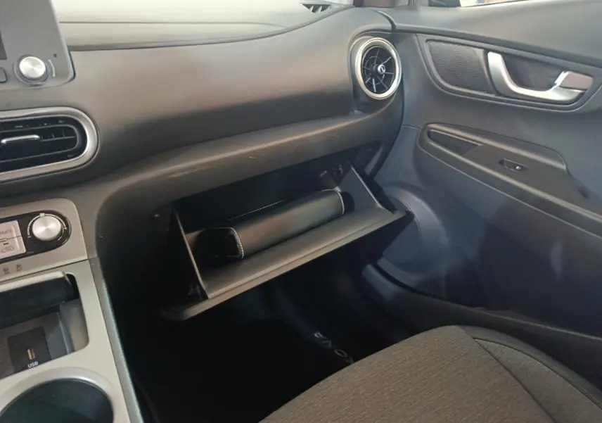 Intérieur côté passager du Hyundai Kona électrique 2022, boîte à gants ouverte avec pochette noire visible.