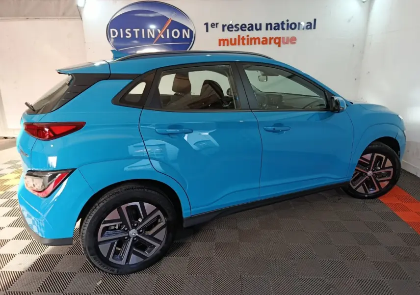 Vue de profil côté droit d'un Hyundai Kona électrique bleu 2022, avec jantes spécifiques et toit noir contrastant.