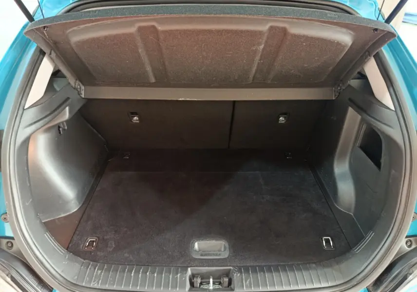 Coffre ouvert vu de l'arrière d'une Hyundai Kona électrique bleu 2022, espace de chargement vide et propre.