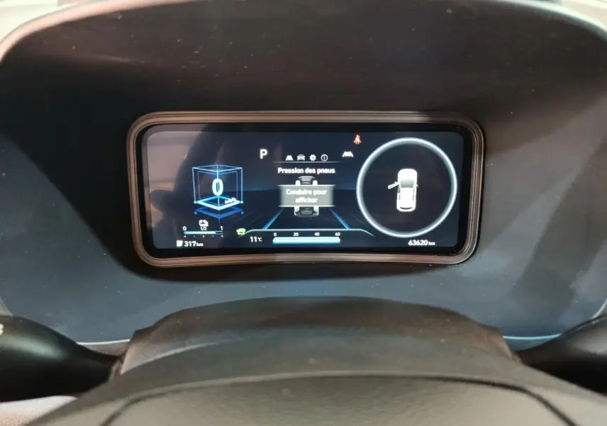 Vue rapprochée du tableau de bord numérique du Hyundai Kona électrique 2022, affichant la pression des pneus et l'autonomie.
