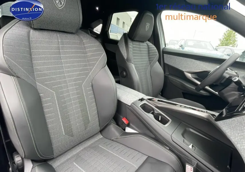 Vue intérieure du Peugeot 3008 blanc 2025, sièges avant en tissu gris et cuir avec logo Peugeot brodé.