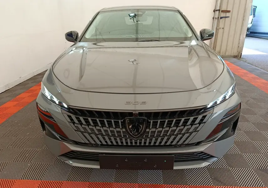 Vue avant frontale d'une Peugeot 308 gris foncé avec calandre distinctive et phares LED fins.