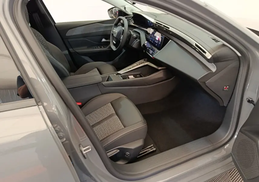 Intérieur avant droit de la Peugeot 308 gris foncé 2026, avec volant cuir multifonctions et écran tactile central.