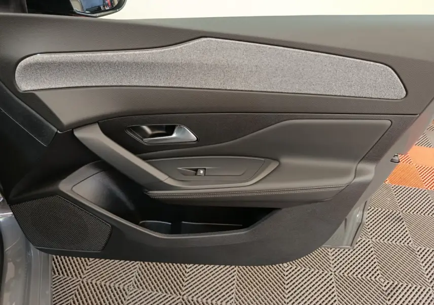 Vue intérieure côté gauche de la porte arrière gris foncé de la Peugeot 308 2026 avec insert tissu clair et poignée métal.
