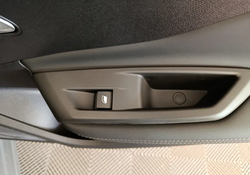 Détail de la commande de lève-vitre sur la porte intérieure noire d'une Peugeot 308 gris foncé, version 2026.