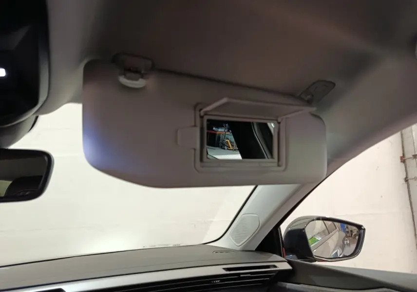 Intérieur Peugeot 308 2026, vue côté passager avec pare-soleil gris ouvert et miroir de courtoisie visible.