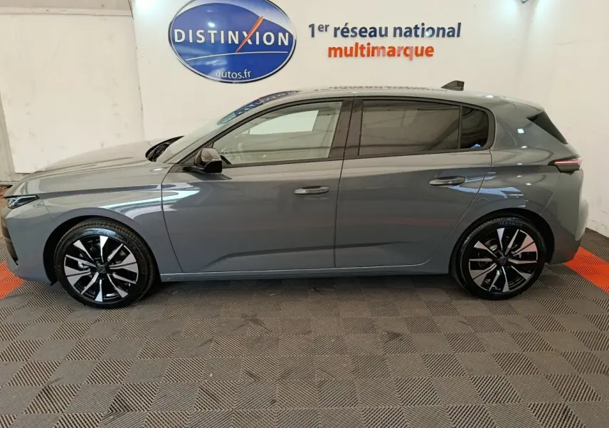 Peugeot 308 BlueHDi 130 gris foncé vue de profil côté gauche, jantes alliage noires et grises, intérieur visible.