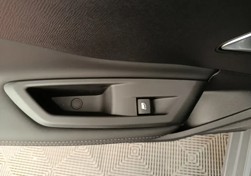 Détail de la commande de lève-vitre côté porte intérieure d’une Peugeot 308 gris foncé, finition cuir.