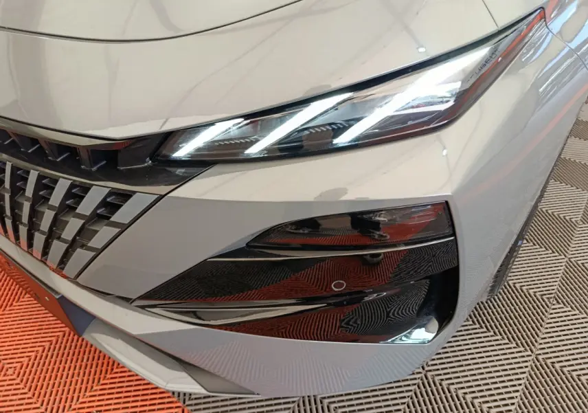 Gros plan sur l'avant droit gris foncé du Peugeot 308 2026, mettant en valeur les phares LED et la calandre distinctive.